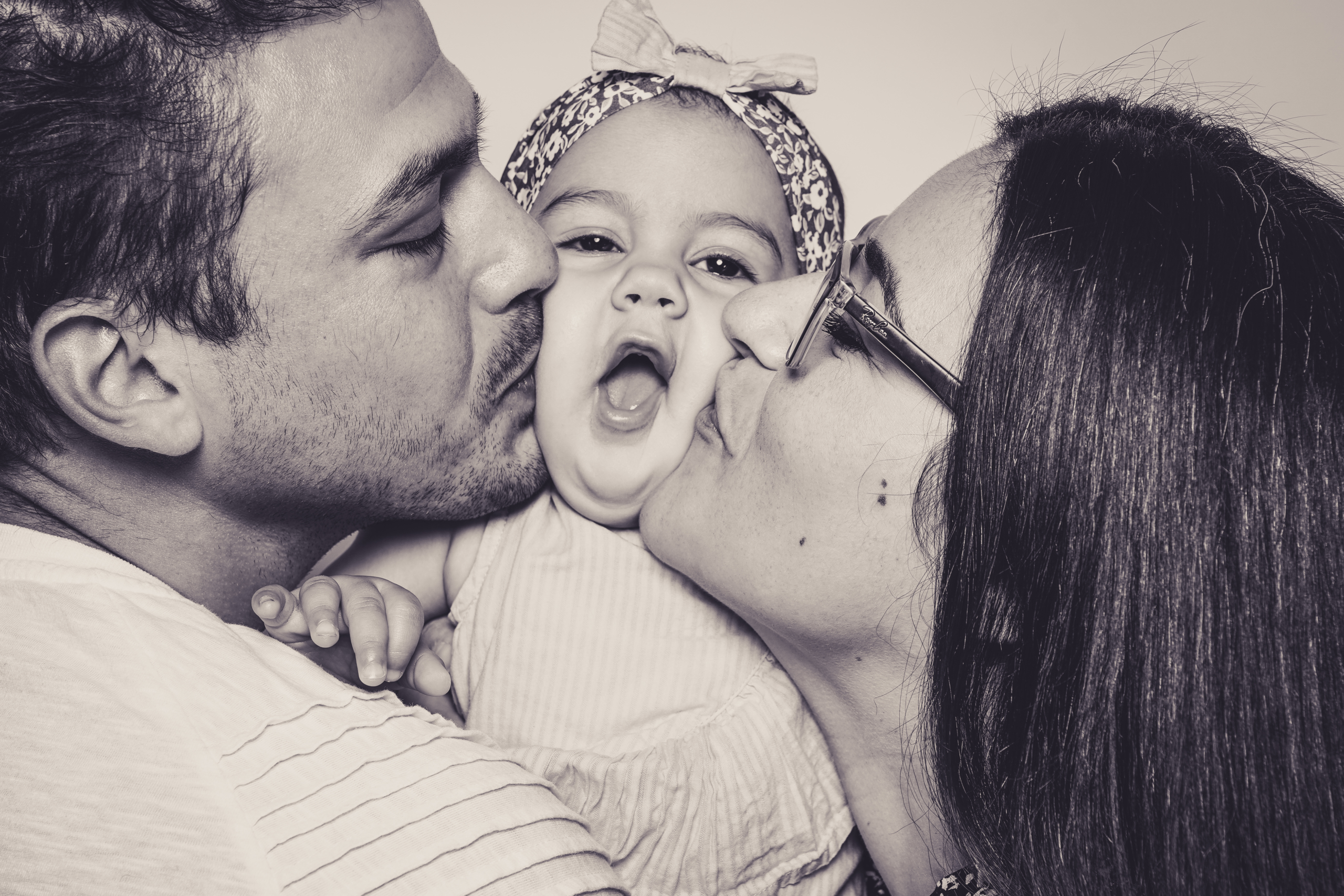 Dicker Kuss für das Baby von Papa und Mama im Fotoshooting