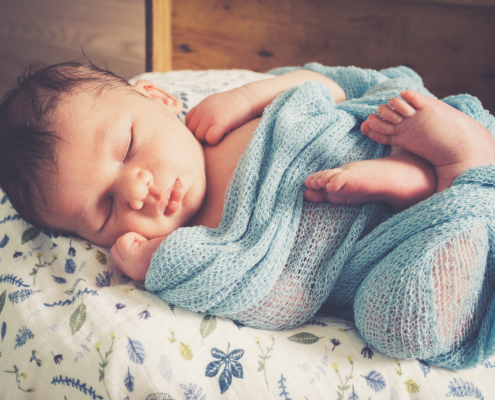 Newborn Fotoshooting Baby schlafend und eingewickelt in Decke